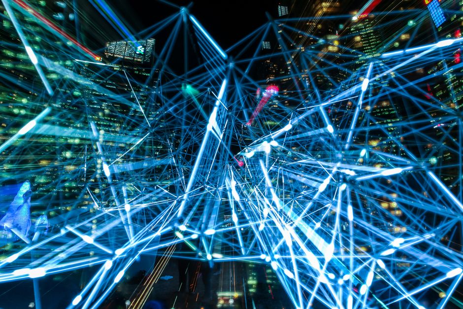 Urbana scena s isprepletenim svjetlosnim tragovima koji predstavljaju digitalne mreže