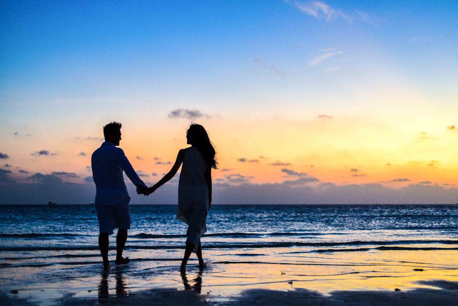 A romantic couple walks hand in hand on a tropical beach at sunset, enjoying a serene moment together